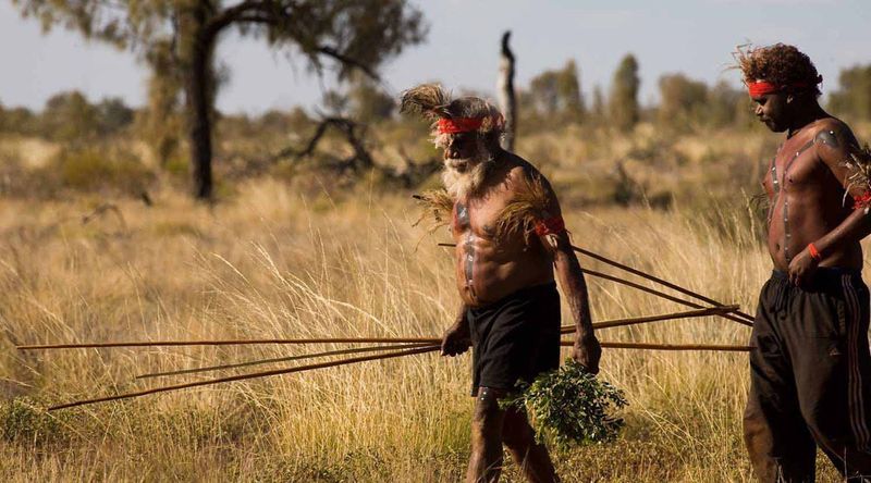 Anangu men carrying long spears.