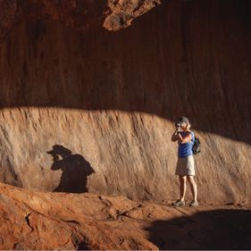 Woman with a digital camera taking a long shot of Uluru